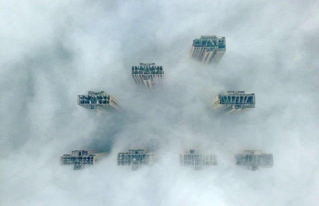 Верхушки высотных зданий видны в густом тумане. Янчжоу, Китай