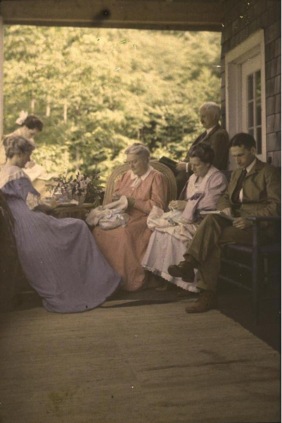 1915. Шесть человек сидят на крыльце, читают и шьют