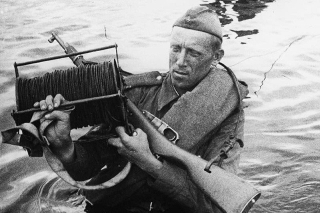 Советский связист прокладывает кабель через реку во время боев на Курской дуге, 1943 год.