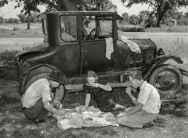 Сезонные рабочие обедают рядом со своей машиной (Ford Model T), в округе Линкольн, штат Оклахома, июнь 1939 года