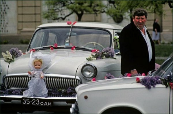 Водитель со своей машиной, украшенной свадебными цветами и куклой, ждет жениха и невесту после их свадьбы. Одесса, Украина, 1982. Автор фото: Иэн Берри