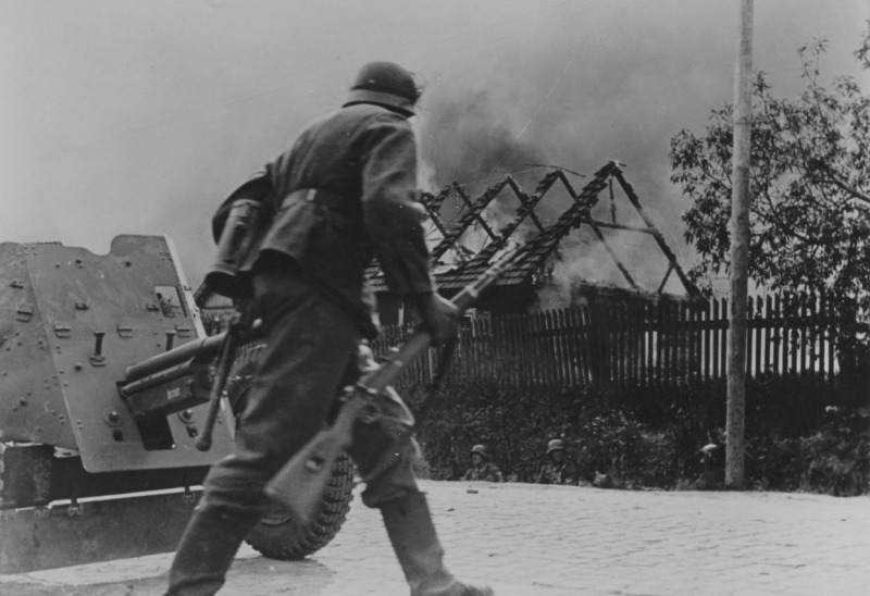 Немецкий солдат переходит улицу горящей советской деревни, лето 1941